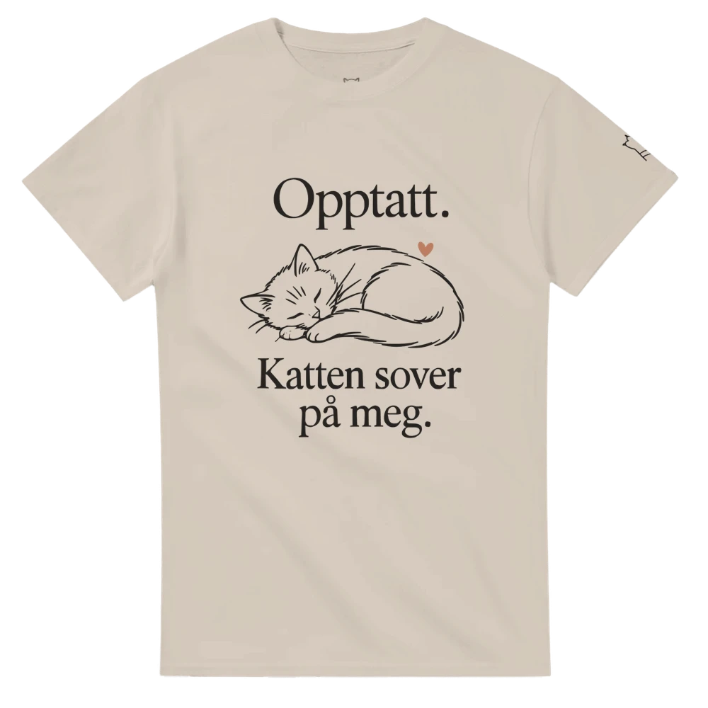 Sandfarget t-skjorte med «Opptatt. Katten sover på meg.» og sovende katt på forsiden